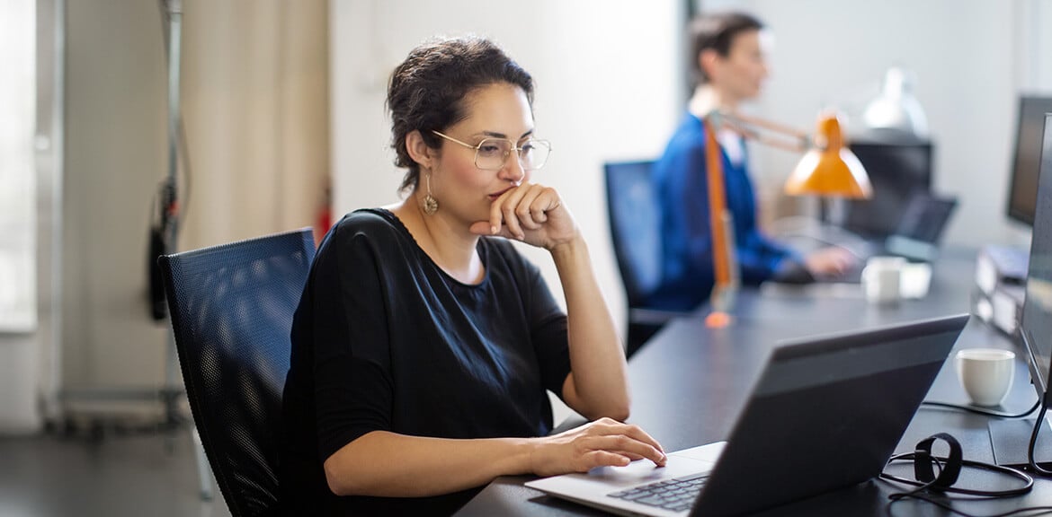 A person sitting at a table using a laptop for online security research